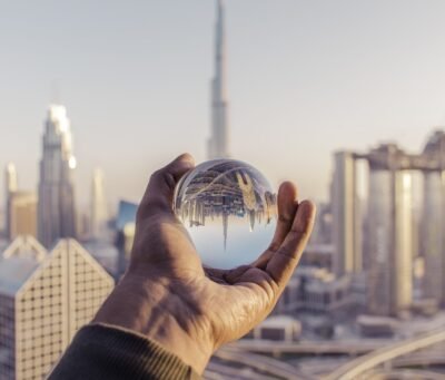 A closeup shot of a male hand holding a crystal ball with the reflection of the city
